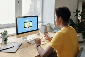 Man working at desk with computer displaying email icon.