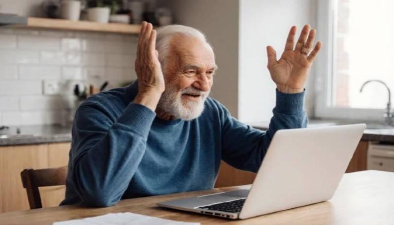 Elderly man surprised or excited while using laptop at home.