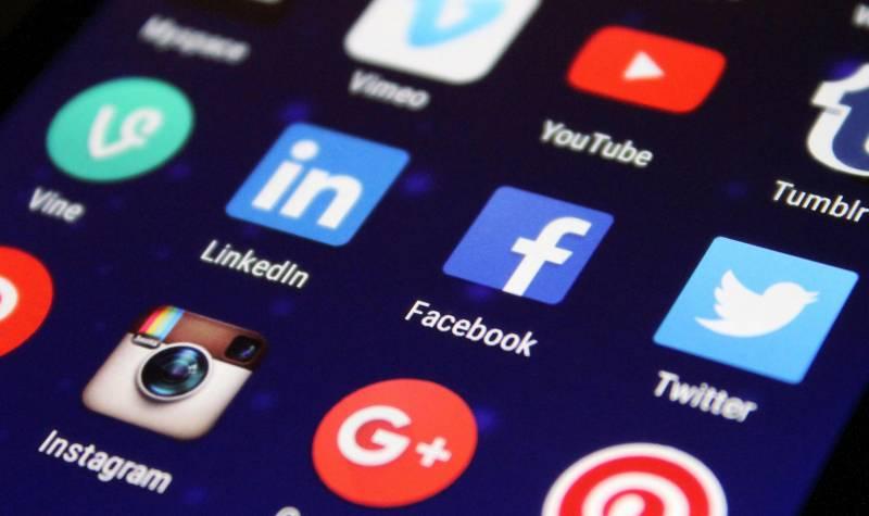 Social media app icons on a smartphone screen, including Facebook, Twitter, Instagram, LinkedIn, Vine, YouTube, Vimeo, Google+, and Tumblr.