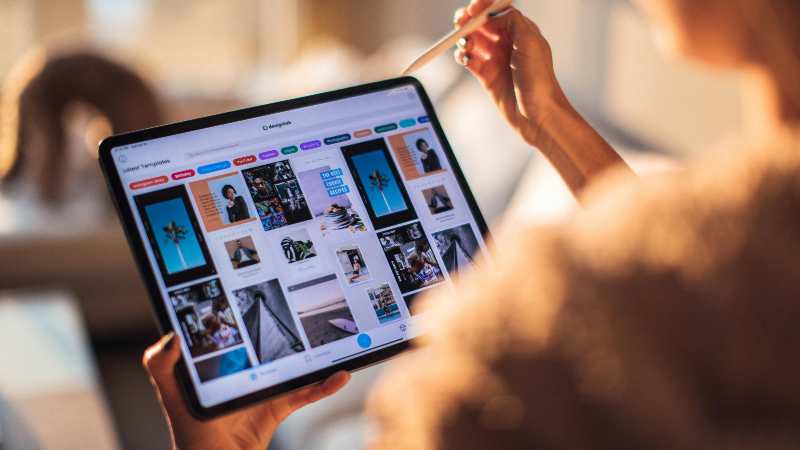 Person using a tablet with stylus to browse images.