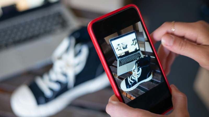 Person taking photo of sneakers with phone camera.