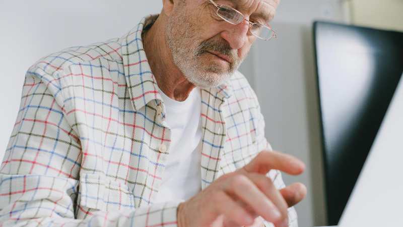 Man in plaid shirt using laptop, focused expression.