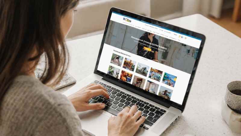 Woman using laptop with images displayed on screen.