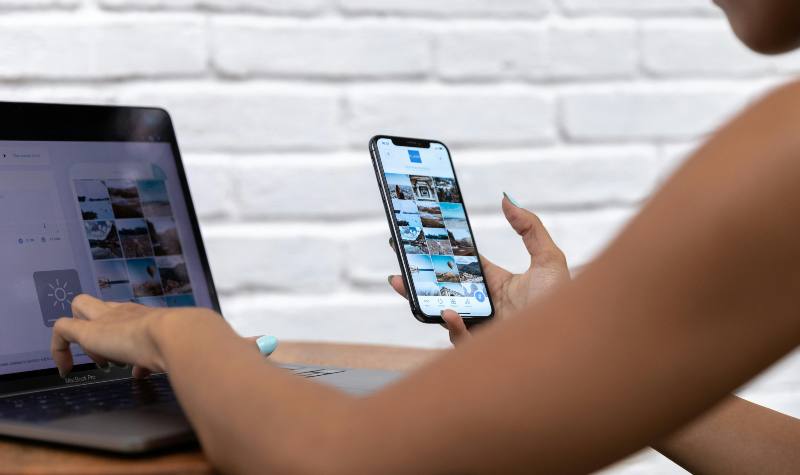 Person using laptop and smartphone to view images simultaneously.