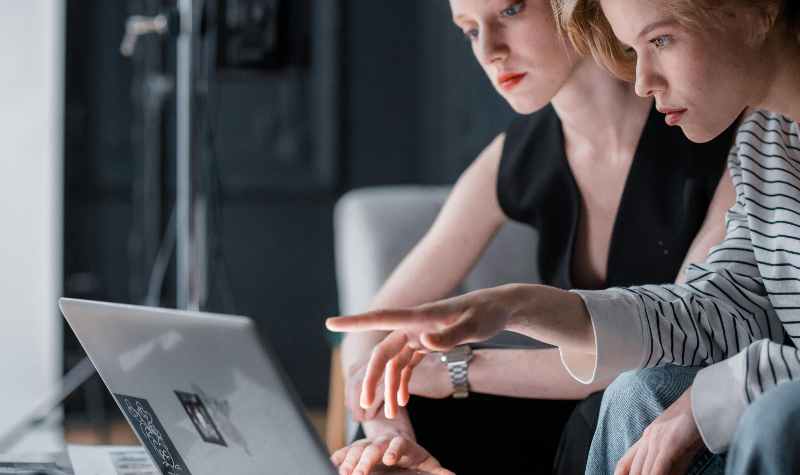 Two individuals collaborating at a laptop in a professional setting.