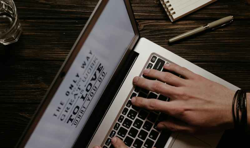 Person typing on laptop with motivational quote on screen.