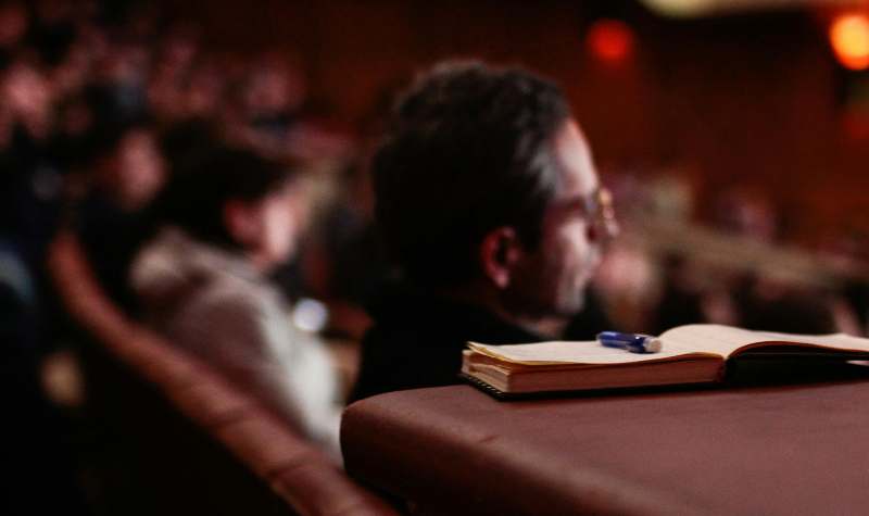 Audience member with notebook and pen at an event.