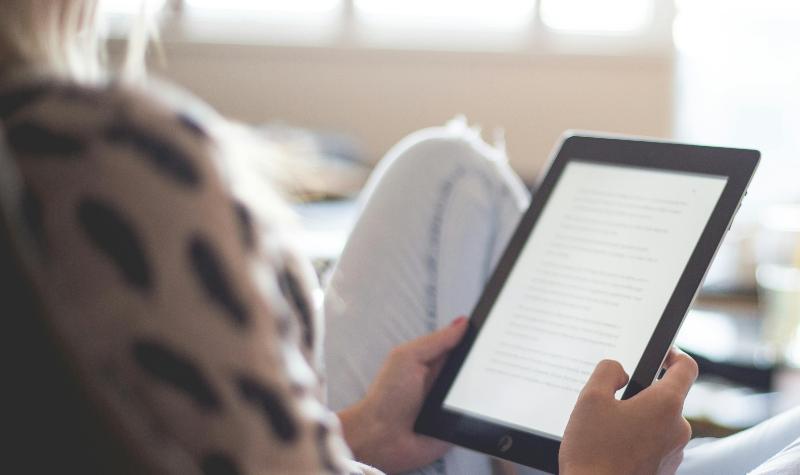 A person reading on an e-reader while sitting comfortably indoors.