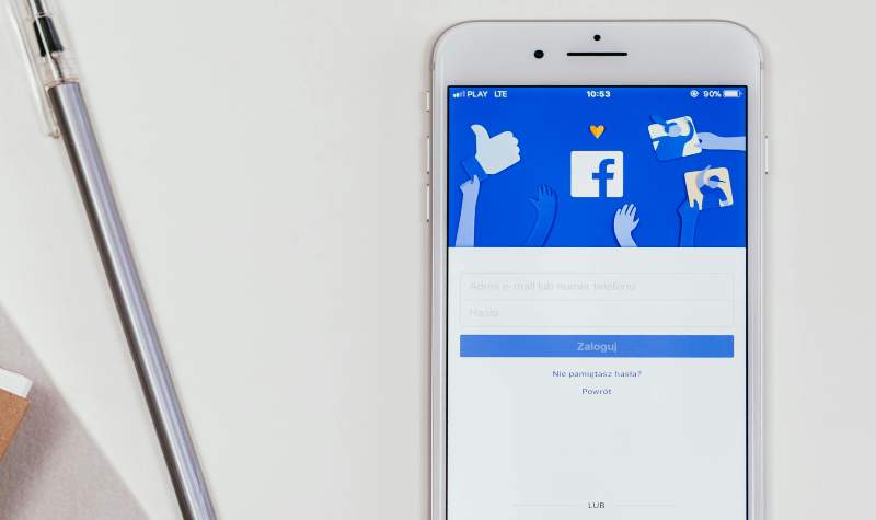 A smartphone displays the Facebook login screen with a pen beside it.
