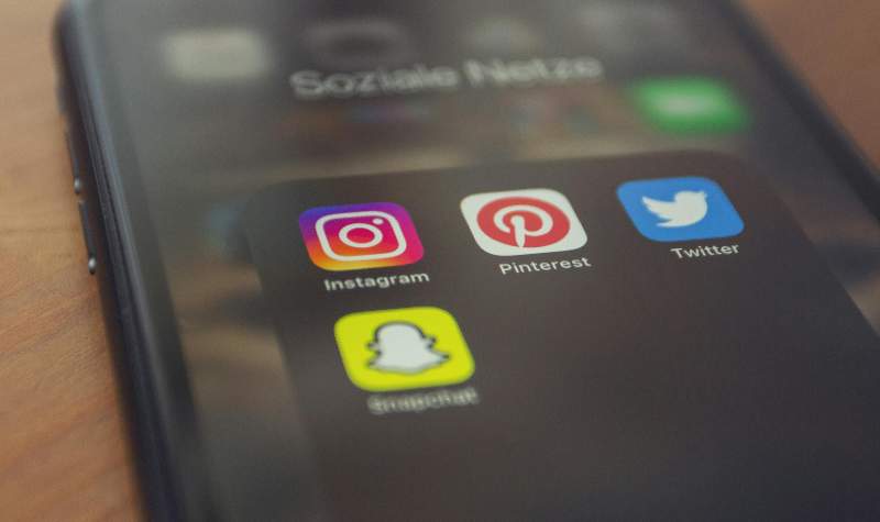 Smartphone screen showing social media apps like Instagram, Pinterest, Twitter, and Snapchat.
