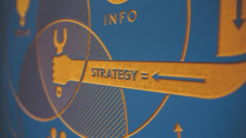 A blue infographic with orange elements shows a hand holding a wrench, labeled "Strategy," with an arrow. The word "Info" is visible at the top.