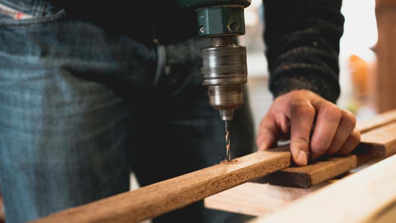 Man drilling into wood with power tool.